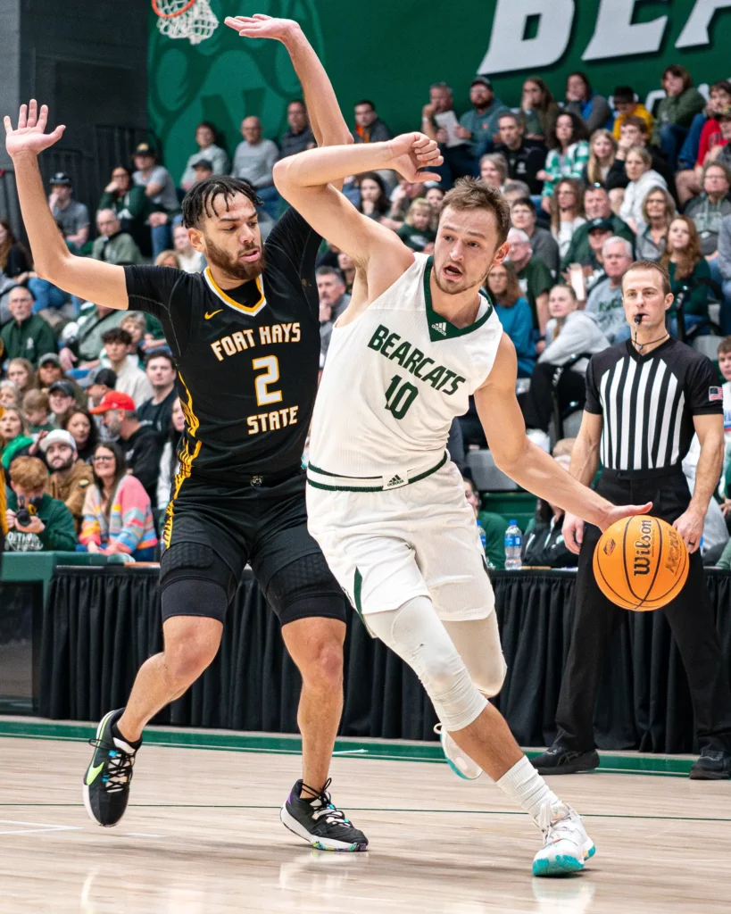 Bearcat men’s basketball forward Wes Dreamer maneuvers around a defender while dribbling along the baseline.