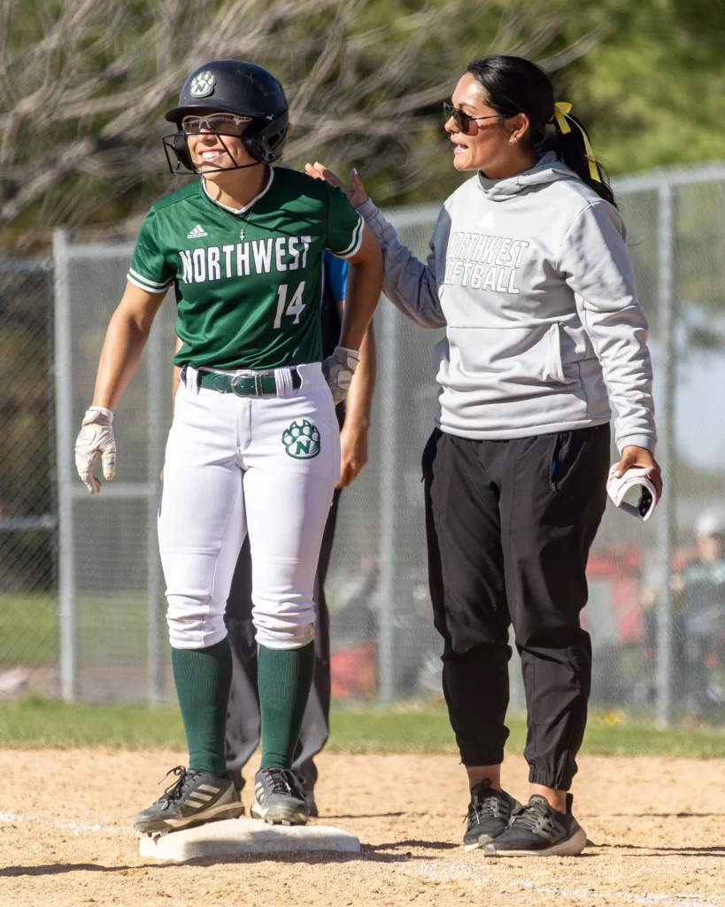 Northwest softball outfielder Lillie Filger is congratulated by coach Naomi Tellez for hitting a single.