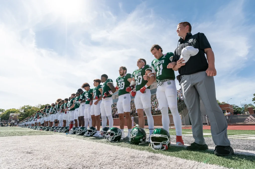 The Bearcat football team stands on the field for the Pledge of Allegiance.